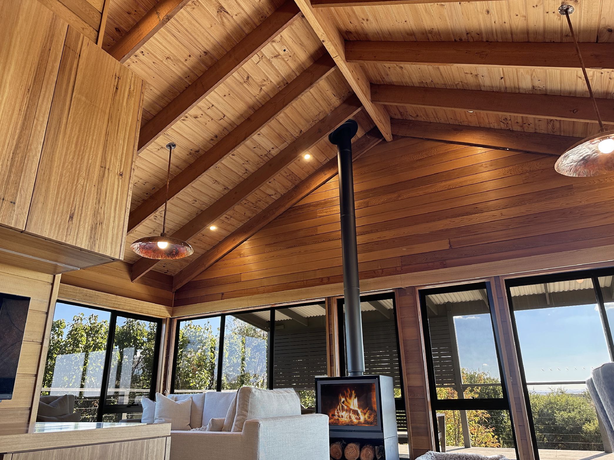 Modern living room with exposed beams, fireplace and large windows